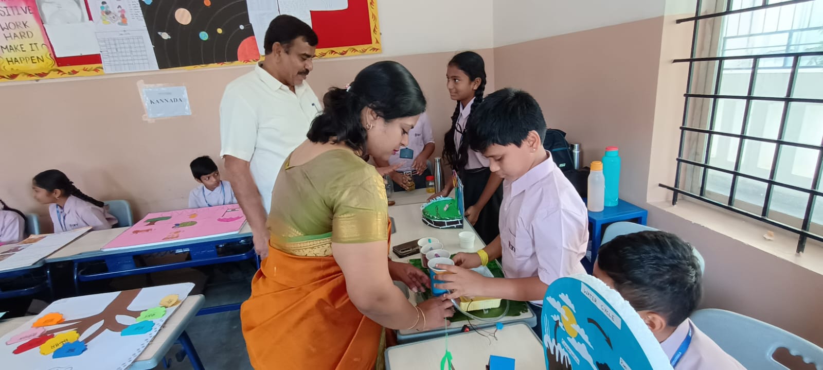 Teacher guiding students in arts and crafts for holistic development